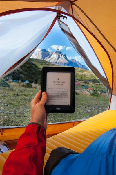 人拿着黑色的亚马逊Kindle电子书阅读器白天的帐篷里
